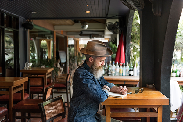 A traveler pausing to write in a journal outdoors, afternoon light falling across the page